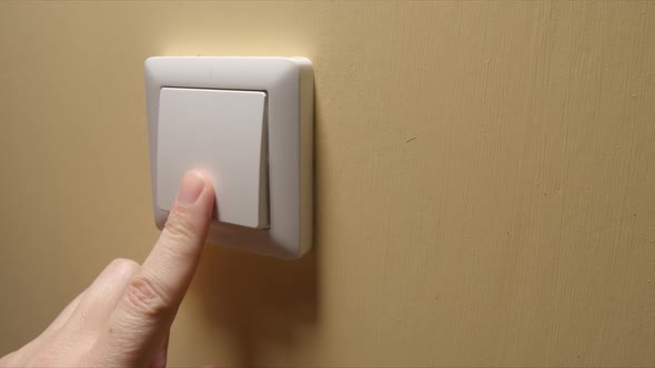 Human hand turn off a power button on a yellow wall
