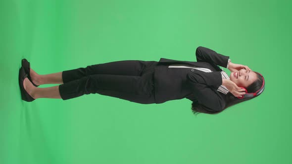 Full Side View Body Of Asian Business Woman Listening To Music And Dancing On Green Screen Studio alt