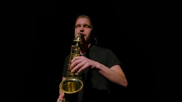 Orbital Shot of a Saxophonist Playing a Golden Wind Instrument in the Dark alt
