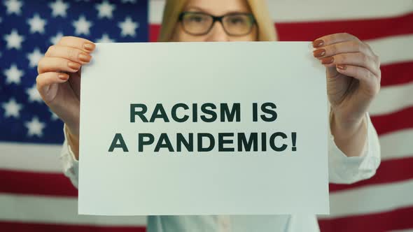 Young Woman Holds Poster Racism Is Pandemic on American Flag Background. Human Rights Demonstration alt