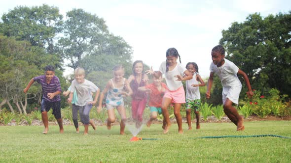 Kids playing with garden sprinkler alt