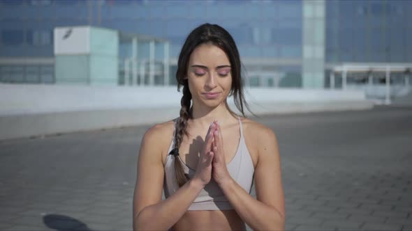 Woman Meditating on City Street. Girl Sitting in Lotus Pose on Mat Outdoors alt