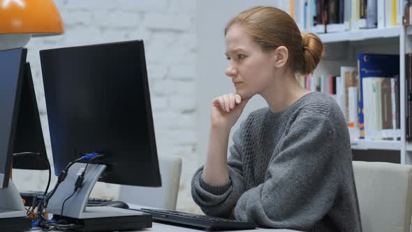 Thinking Redhead Woman Working on Laptop, Sitting In Office alt
