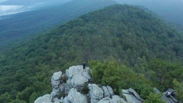 Man stands on top of Big Schloss - Virginia - Dawn - Aerial alt