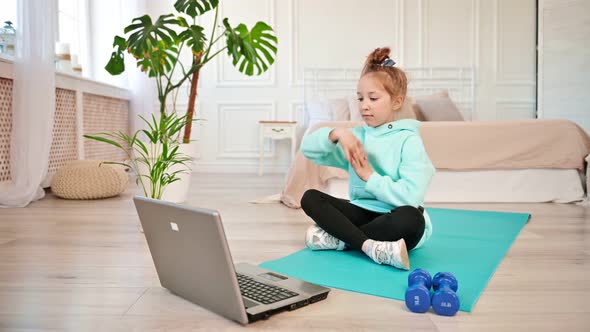 Concentrated Girl 810 Years Old Doing Sports in Front of a Laptop Screen