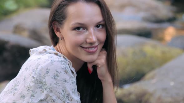 Beautiful girl sitting on stone in forest