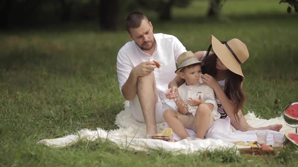 Parents and Their Son Eating Bakery at Picnic.