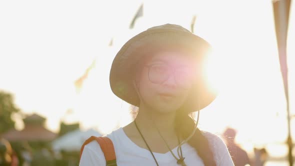 Young Asian woman smiling looking at camera over sunset background.