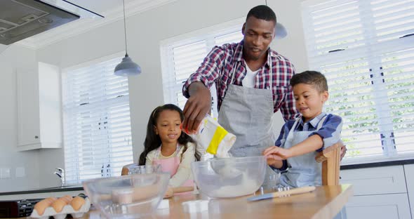 Front view of black father with his children preparing food in kitchen 4k alt