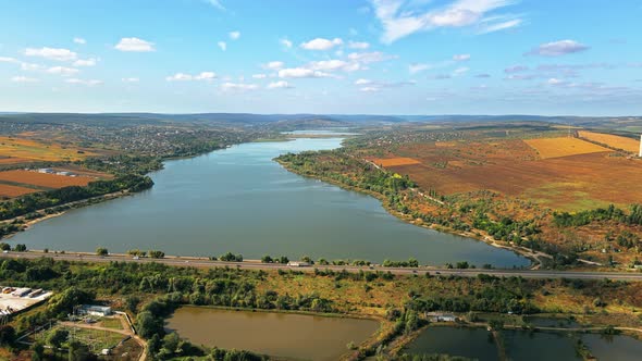 Aerial drone view of nature of Moldova. Lake, villages, highway with multiple moving cars alt