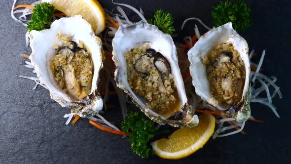 Fried Oysters in Shells with Garlic and Lemon on Black Textured Slate Background alt