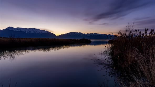 Night-to-day sunrise timelapse with stunning light changes at a river flowing gently into a lake alt