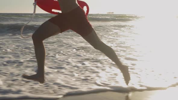 Male lifeguard running along the beach alt