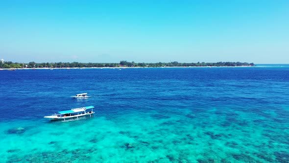 Touring boats floating on beautiful blue azure sea with rocky bottom seen through clear water around alt