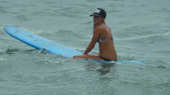 A young woman surfing in a bikini on a longboard surfboard. alt