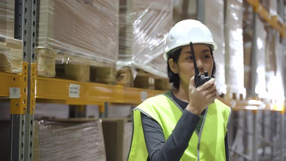 Asian Female Warehouse Worker with Walkie Talkie Talking Discussing on the Radio alt