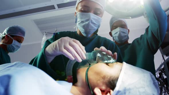Surgeon putting oxygen mask on patient in operation room alt