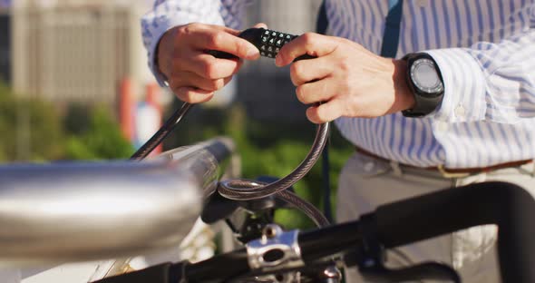 Mid section of asian man locking his bicycle at corporate park alt