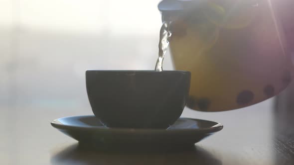 Pouring Fruit Tea in Mugs at a Cafe