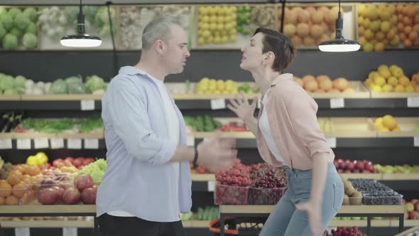Side View of Nervous Man and Woman Arguing Emotionally in Grocery. Portrait of Argued Caucasian alt