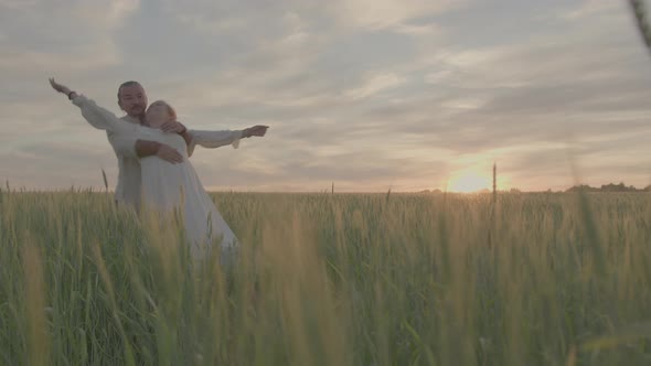A Heterosexual Slavic Family in Folk Costumes on a Green Wheat Field at Sunset