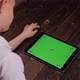 Closeup of a Child Holding a Tablet with a Green Screen on a Wooden Background - VideoHive Item for Sale