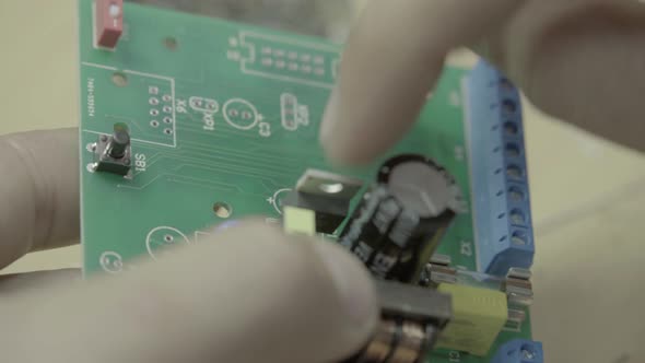A Worker Is Working on the Production of an Electronic Board. Close-up. alt