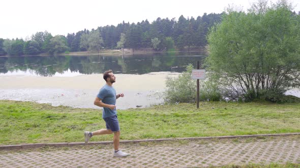 Athletic man jogging by the lake. alt