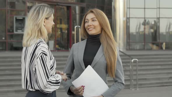 Two Businesswomen Sealing the Deal with Handshake in Front of Office Building alt