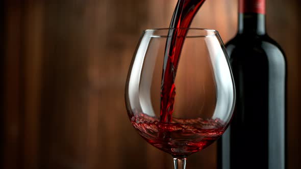 Super Slow Motion Detail Shot of Pouring Red Wine on Wooden Background at 1000Fps alt