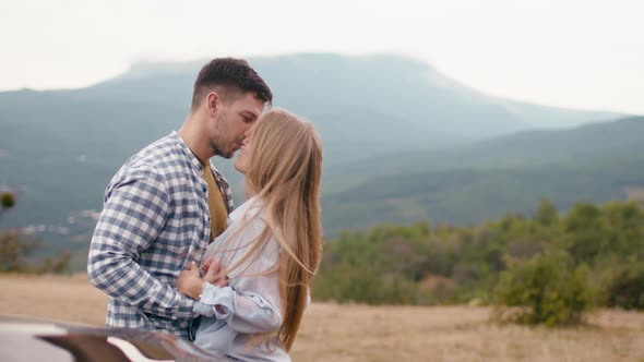 Young Loving Couple Standing and Hugging in Mountains