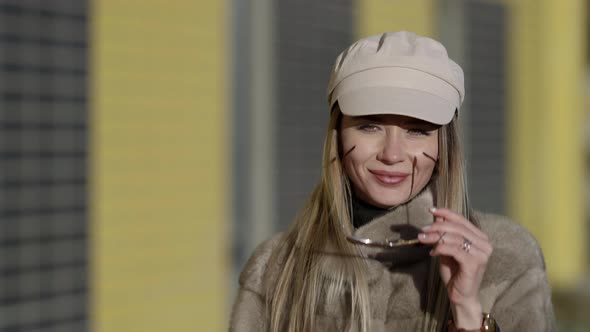 Charming Lady Is Putting Sunglasses Walking at Autumn or Early Spring Day at Sunny Weather alt