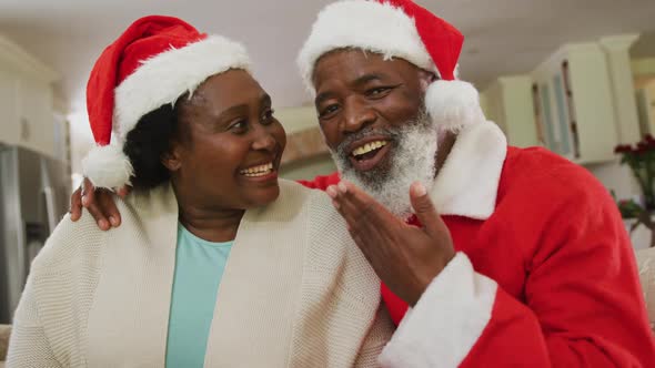 Portrait of african american couple at christmas time wearing santa hats alt