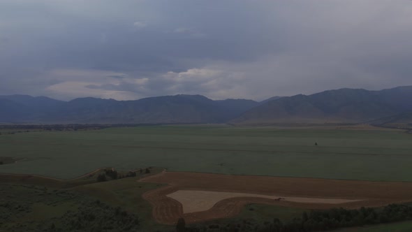 Agriculture and green fields in valley of Altai under thunderstorm sky