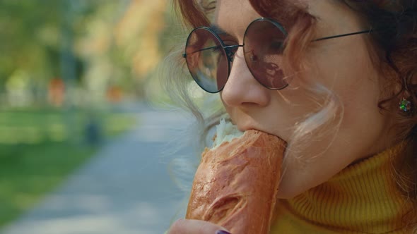 Young Happy Woman Eating Baguette in City Park alt
