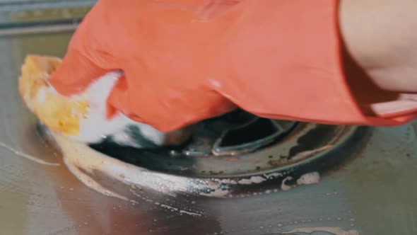 Housewife in Gloves Washes the Dirty Surface of a Gas Stove with a Washcloth alt