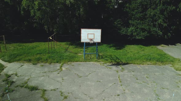Boards. Peeling Paint And A Battered Basket. There Is An Old Cracked Asphalt On The Site. alt