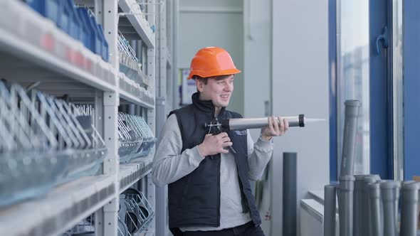 Portrait of Joyful Young Hardware Store Worker Having Fun Using Caulking Gun As Weapon alt