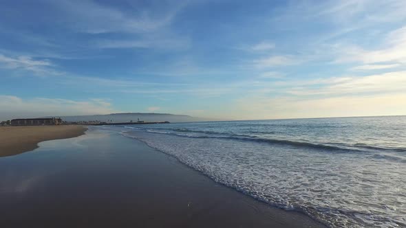 Aerial shot of a scenic beach shoreline at sunset. alt