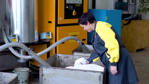 Production Plant Worker Works with Loader Hose Vacuum Sucking White Virgin Plastic Granules From