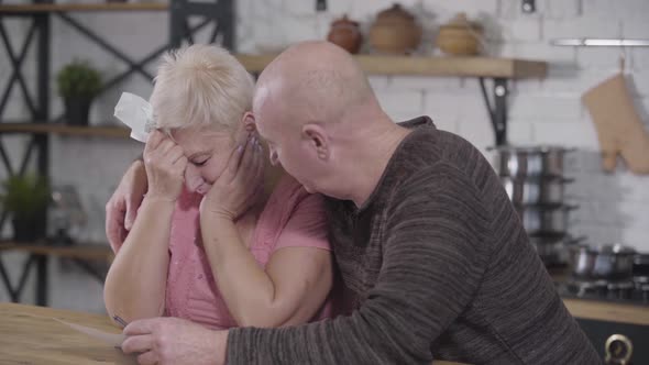 Side View of Mature Caucasian Couple Settling Their Income and Expenses. Senior Man Calming Down alt