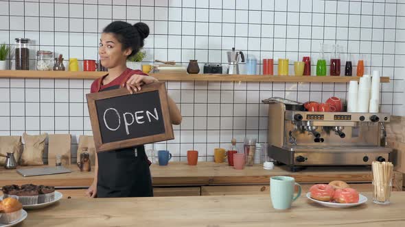 Barista Holding Blackboard in Hands with Sign "open" on It