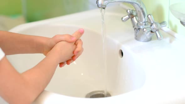 child washes his hands with soap with a bath.