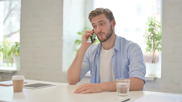 Young Creative Man Talking on Smartphone in Modern Office alt
