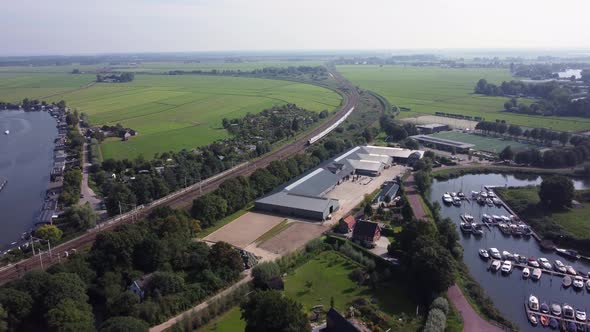 Train driving trough Dutch landscape along harbor at city Weesp, Aerial alt