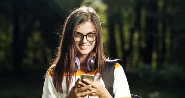 Young Woman Holding Smartphone in Park