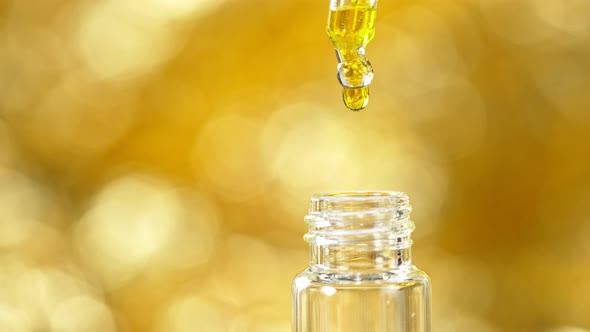 Super Slow Motion Shot of Oily Essence Drop Into Phial on Golden Background at 1000Fps alt
