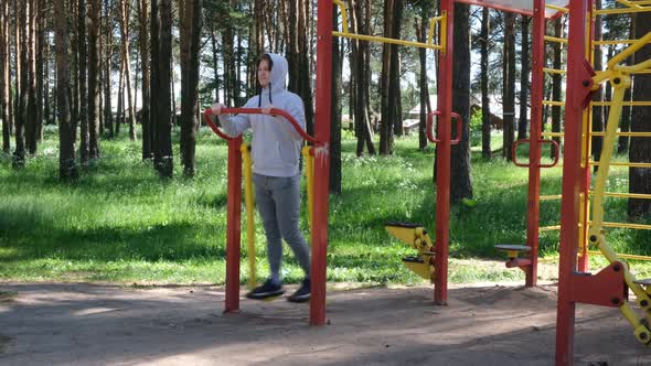 Single Young Man Doing Exercises at Street Gym Apparatus in Park Street Workout