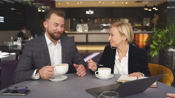 Handsome Businessman and Elegant Businesswoman Having Pleasant Conversation for a Cup of Coffee