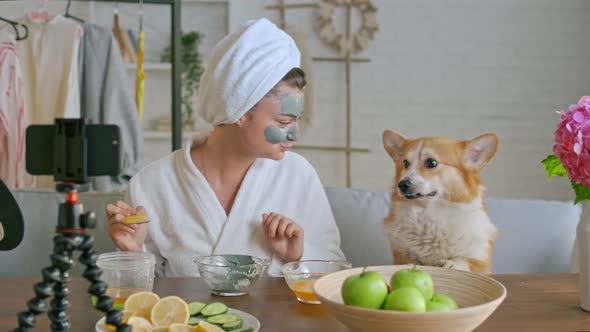 A Girl With a White Towel Put on Her Face a Green Mask During Blogging alt